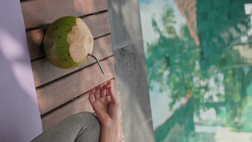 Young woman meditating at the pool side, fresh green coconut is ready for drinking | Shutterstock HD Video #1109166887