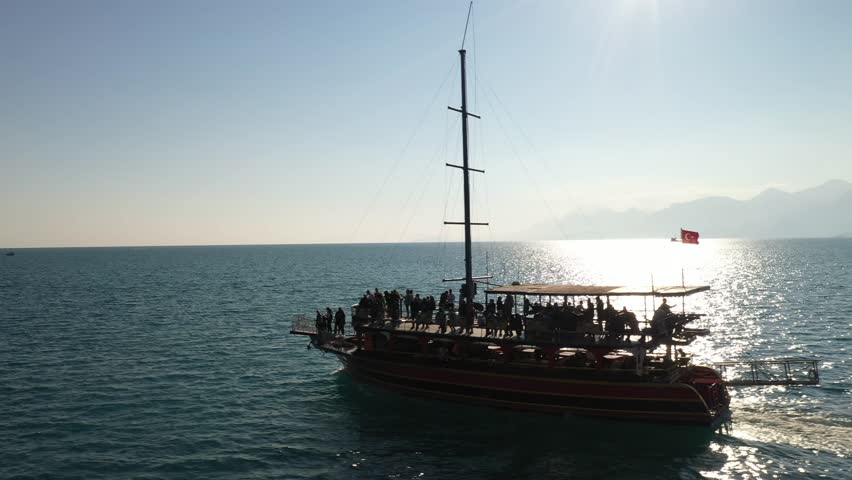 A drone footage of a boat ride on Sea of Galilee in Israel with rocky cliffs with trees in daytime