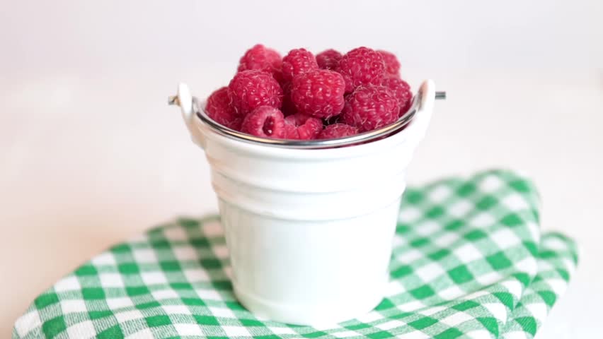 Fresh raspberries in a white bucket on a light background, rotating. raspberry, rotation in circle. raspberry in a bucket, on a green napkin | Shutterstock HD Video #1109170415