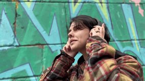girl teenager in headphones on the background of graffiti smiles. music art freedom youth concept. brunette teenager girl walking past a wall with graffiti listening music lifestyle with headphones - Powered by Shutterstock - Get 15% off with code: PIKWIZARD15