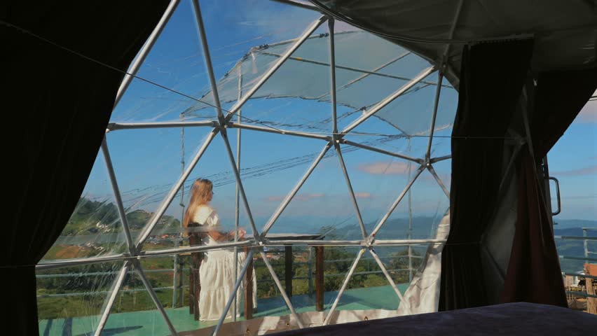 Young woman relaxes outside bubble tent at majestic mountains. Summer vacation in countryside, perfect for outdoor lovers and adventure seekers. Inspire wanderlust.