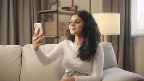 Portrait of beautiful young woman having video call conference meeting interview by smartphone at home Confident curly female talking on pleasant conversation having distance remote relationships