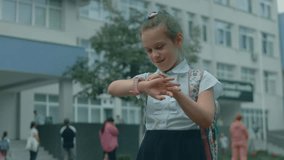 Beautiful caucasian school girl using smartwatch outdoor in school park. Child talking with her parent on video call on the smartphone. Smart wristwatch with GPS tracker.