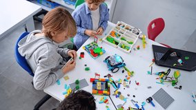 Robotics programming class. Children construct and code Robot. STEM education using constructor blocks and laptop tablet, remote control joystick. Technology educational development for school kids - Powered by Shutterstock - Get 15% off with code: PIKWIZARD15