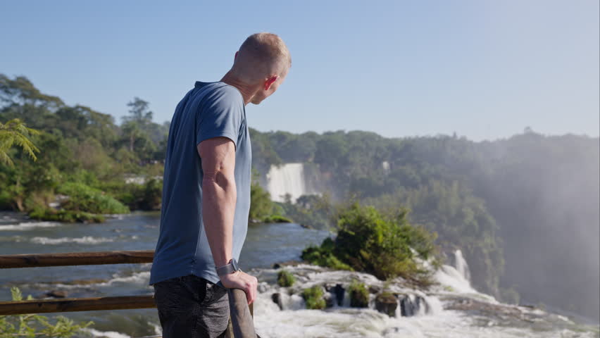 A man, who is a tourist, standing on a viewing deck.