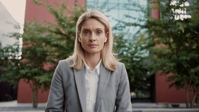 Front view of confident business lady in stylish formal wear and wireless earphones sitting outdoors and talking during video conference. Online meeting of partners outside office building. - Powered by Shutterstock - Get 15% off with code: PIKWIZARD15