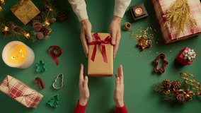 Male hands giving present gift wrapped in golden shiny paper with red bow to female hands. Person holding box tied with red ribbon. Concept of family holidays, perfect Christmas, New Year, celebration - Powered by Shutterstock - Get 15% off with code: PIKWIZARD15