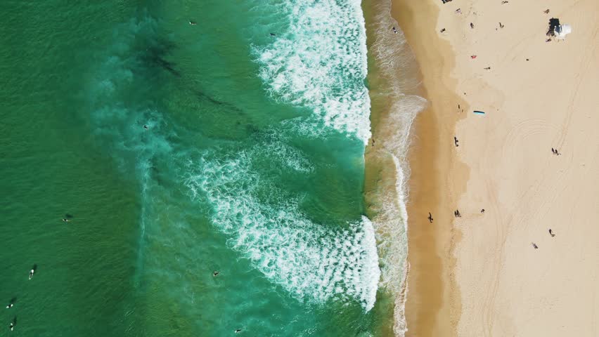 Bondi beach in Sydney, Australia. Aerial view moves along the coastline as waves crash onto the white sand where people are enjoying the beach. Royalty-Free Stock Footage #1109188377