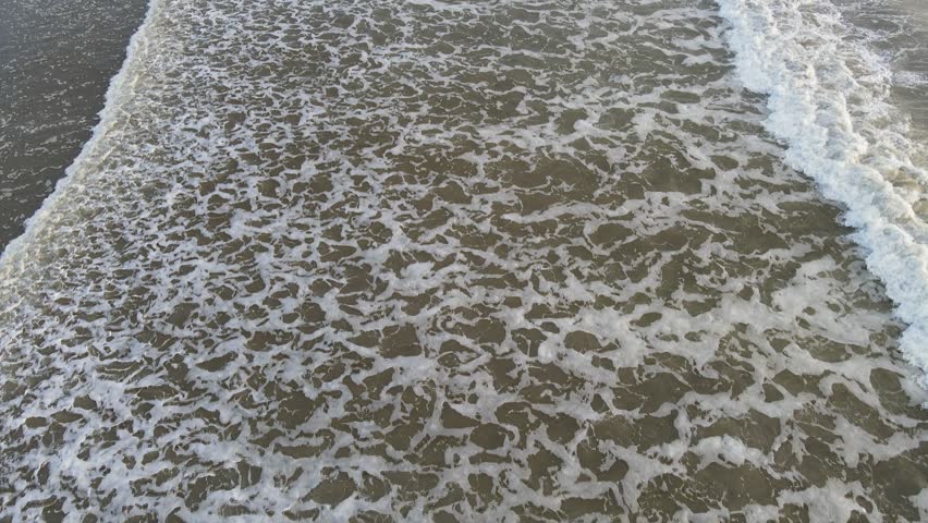 Waves crashing on the beach of Tamarin Bay with a view tilting towards La Tourelle mountain.