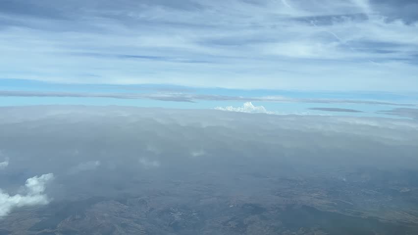 Flying between layers of clousds in a sunny autumn afternoon, shot from an airplane cockpit at 5000m high. A pilot’s perspective.