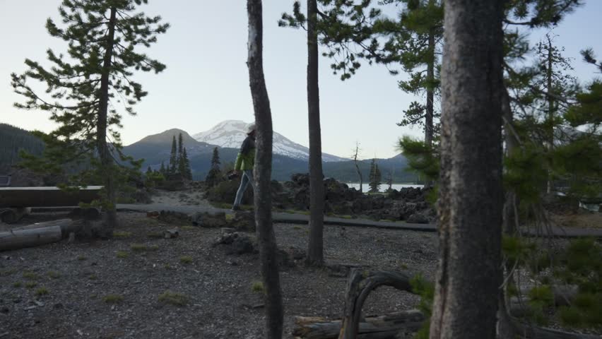 Man Walking besides scenic lake as camera follows along