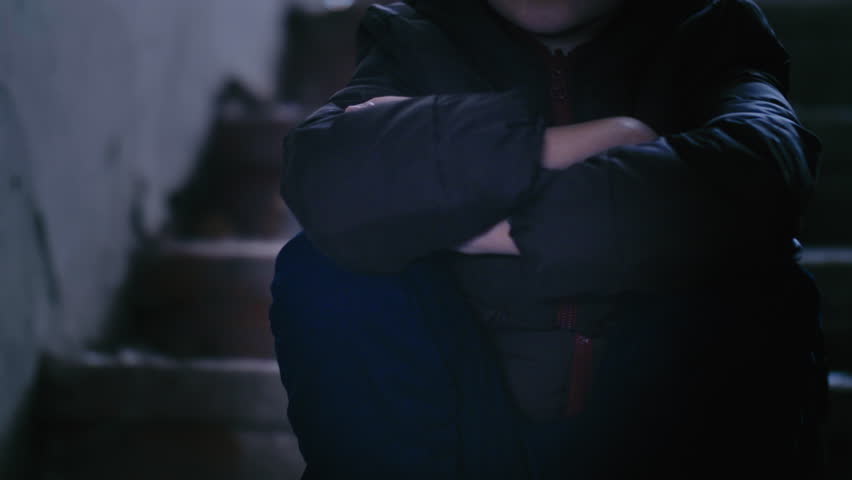 Teen Boy Sitting in a Ruined House, Gazing into the Distance