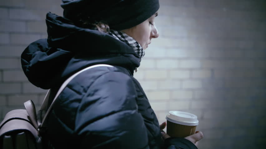 Coffee Bliss in Winter's Embrace: Woman's Serene Walk through the Underground, Sipping Warmth Royalty-Free Stock Footage #1109210569