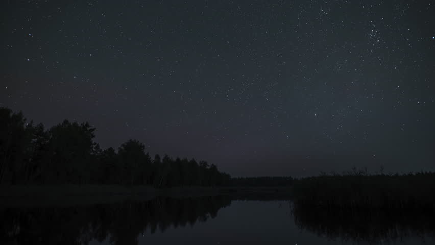 Timelapse of the stars move in the night sky over the lake. Stars move around a polar star. Epic video 4K