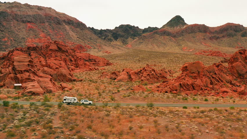Aerial view of a truck with trailer driving on a road in middle of red rocks in Nevada, USA