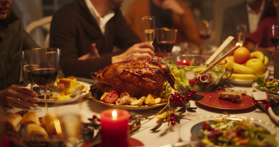 Festive Thanksgiving Dinner or Christmas Celebration Family Meal. People Sitting Behind a Dining Table with a Turkey Feast, Baked Potatoes, Side Dishes and Drinks. Close Up Footage of a Tasty Meal Royalty-Free Stock Footage #1109217835