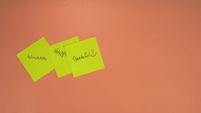 Top-down video of a male hand placing a Kindness sticky note on top of three other notes that say Winner, Happiness Grateful. Positive thoughts concept video clip.