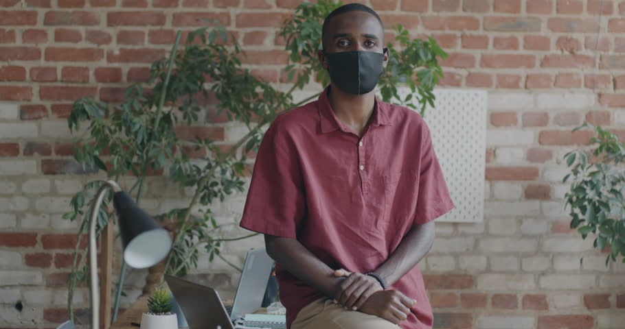 Portrait of African American office worker wearing face mask looking at camera indoors in workplace. Job and pandemic restrictions concept. | Shutterstock HD Video #1109226687