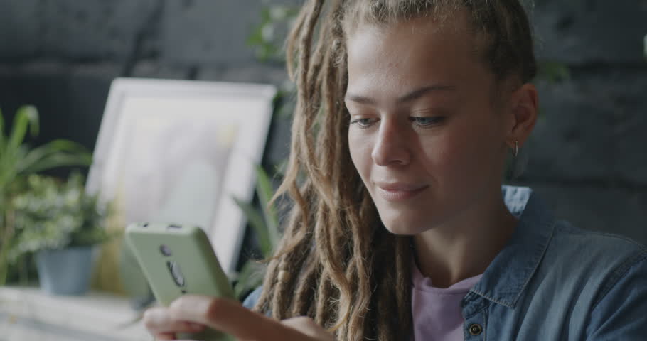 Joyful businesswoman communicating with smartphone touching screen and smiling indoors in loft style office. Modern devices and business concept. | Shutterstock HD Video #1109226695