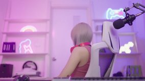 E-sport game online streaming activity, playing cyber games, Happy asian girl gamer wear headphone competition play video game online with colorful neon lights in home living room.
