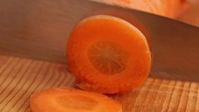 Cutting carrots with a knife on a wooden table. ASMR video of cutting vegetables. Round carrot pieces.