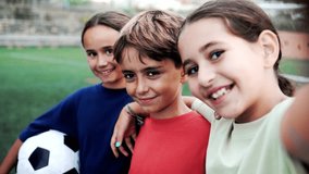 Kid friends after soccer play game having fun taking selfie outside - Latin children celebrating and hugging together - Childhood friendship and sport life style concept