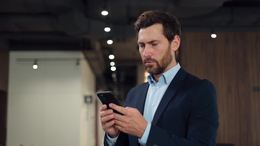 Shocked male trader watching at stock exchange market on smartphone and observing decreasing charts. Formally dressed man feeling despair about losing money. Concept of crisis and inflation. Royalty-Free Stock Footage #1109234703