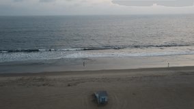 This is a drone shot of the lifeguard tower in Santa Monica beach, California, around sunset time  
 