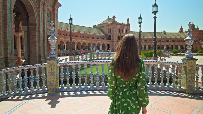 A beautiful tourist girl in a green dress walking in Plaza de España in Seville. Female exploring Historical most famous landmark Plaza España, Sevilla in Spain, Europe Royalty-Free Stock Footage #1109238083