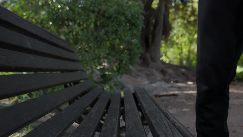 A man sitting down on a park bench, medium close-up | Shutterstock HD Video #1109246519