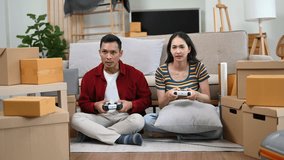 
Asia young couple man and woman sit on couch use joystick controller play video game spend fun time together on sofa in living room. Asian married couple family 