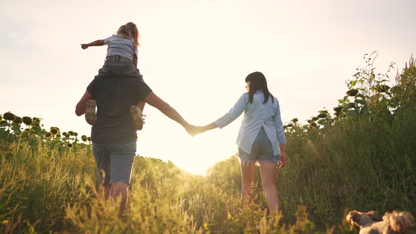 family walking with child. happy family kid dream concept. a family walks with a boy across a field holding hands. friendly family silhouette view from the back walking in the lifestyle park