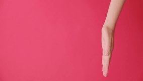 Vertical video of unrecognizable young woman opening and pointing on palm on copy space aside, makes thumb up, isolated over red studio background wall with advertisement. Body language concept