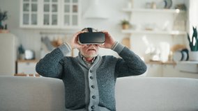 Happy senior man in virtual goggles plays video game touches objects in air in cyberspace. Looks at virtual world in VR helmet. Modern methods of medical restoring motor activity after heart attacks. - Powered by Shutterstock - Get 15% off with code: PIKWIZARD15
