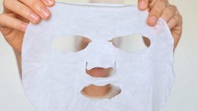 Beauty and skin care. Freshness and purity. Skin rejuvenation treatment. Smiling woman holding applying facial sheet mask taking care of her with perfect skin isolated over white background. - Powered by Shutterstock - Get 15% off with code: PIKWIZARD15
