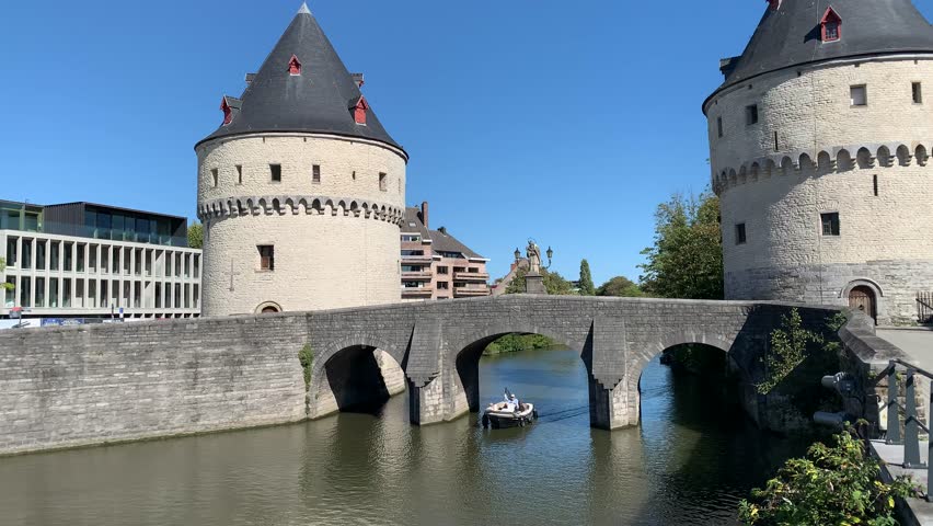 Boat is sailing under the stone bridge between two famous Medieval Broel towers (Broeltorens). Kortrijk city centre. Sightseeing, tourists attraction.  Kortrijk, Belgium