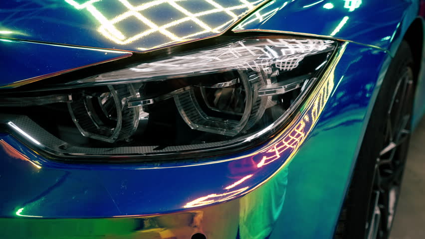 Close-up of headlight wheel and bumper of luxury car covered with protective film in chameleon color at the car wash Royalty-Free Stock Footage #1109266575