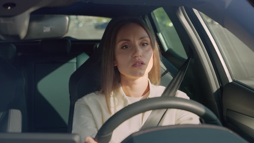 Bad-tempered young lady driving automobile with safety bell and feeling irritated when being cut off on highway. Angry female person yelling, gesturing hands and beeping horn. Royalty-Free Stock Footage #1109267767