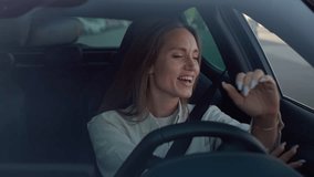 Dynamic young woman with long hair having fun while driving car. Energetic female listening to radio, singing song and making rhythmic movements. Concept of good mood and entertainment. - Powered by Shutterstock - Get 15% off with code: PIKWIZARD15
