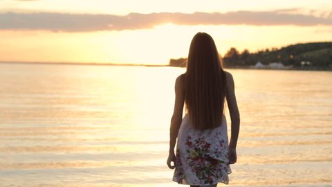 Girl in white dress walk barefoot on hot summer beach