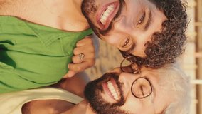 Vertical video, Close-up of young gay couple sitting hugging, smiling and posing for selfie on the beach - Powered by Shutterstock - Get 15% off with code: PIKWIZARD15