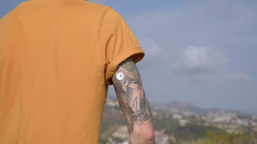 Man with glucose level remote sensor on tattooed arm to control diabetics blood sugar level. Online monitoring glucose levels without blood. Medical technology in diabetes treatment, healthcare.