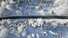 Vertical video. Top view of a scenic road through a snowy winter mountain forest.