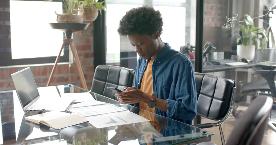 African american casual businessman sitting at desk talking on smartphone at home, slow motion. Communication, home office, remote working and casual business, unaltered. | Shutterstock HD Video #1109275317