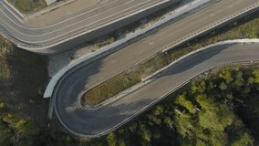 A highway in the mountains, a mountain serpentine, cars are driving along the road and runners are running, video from a drone