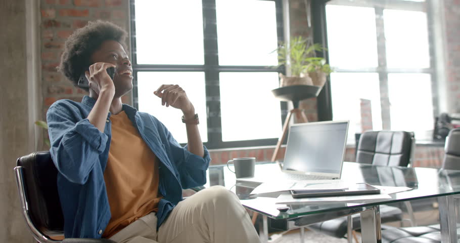 Happy african american casual businessman talking on smartphone at home, copy space, slow motion. Communication, home office, remote working and casual business, unaltered. | Shutterstock HD Video #1109276231