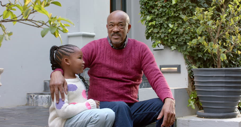 Happy african american grandfather and granddaughter sitting and talking in garden, slow motion. Family, childhood, relaxation and lifestyle, unaltered. | Shutterstock HD Video #1109276537