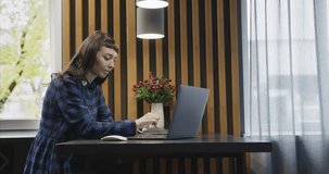 Portrait of a young girl in headphones talking in front of a laptop screen.