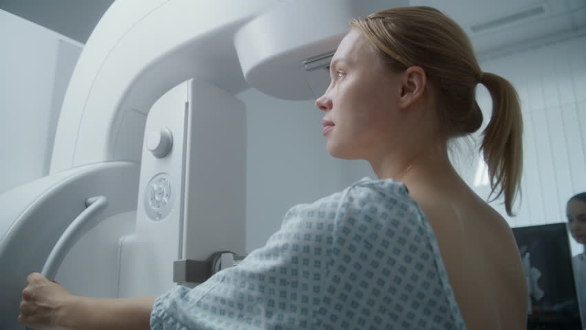 Caucasian adult woman stands in hospital radiology room. Female patient undergoing mammography screening procedure using digital mammogram machine. Breast cancer prevention. Modern clinic equipment. Royalty-Free Stock Footage #1109279475