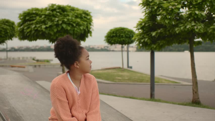 Afro american girl in skate park on the beach in summer. The girl enjoys the morning view and rests after training.